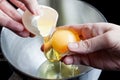 Separating yolk and white of the egg above metal bowl Royalty Free Stock Photo